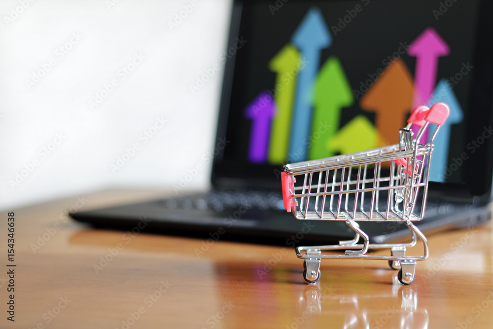 Shopping cart in front of arrows on a laptop