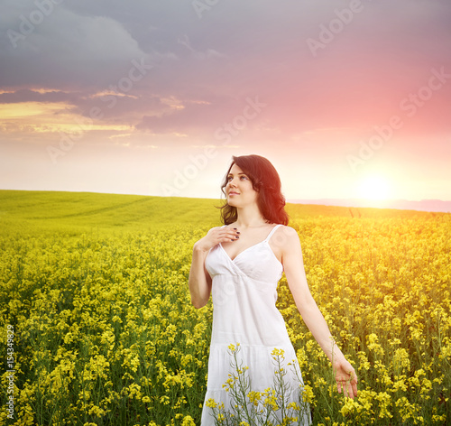 Woman in field with flowers at summer sunset.
