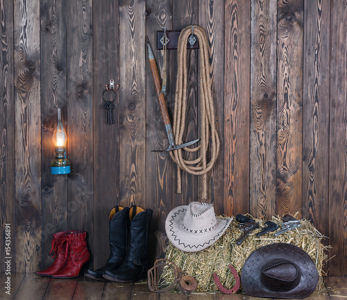 Cowboy hat, boots and weapons on the background of the old barn.Wild west, cowboy,Vintage photo