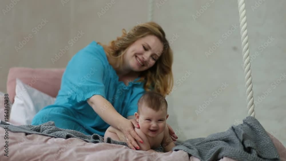 Caring young mother massaging naked baby girl Caring young mother massaging naked baby girl