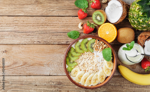 Granola with Greek yoghurt and fruit on a wooden background in a rustic style