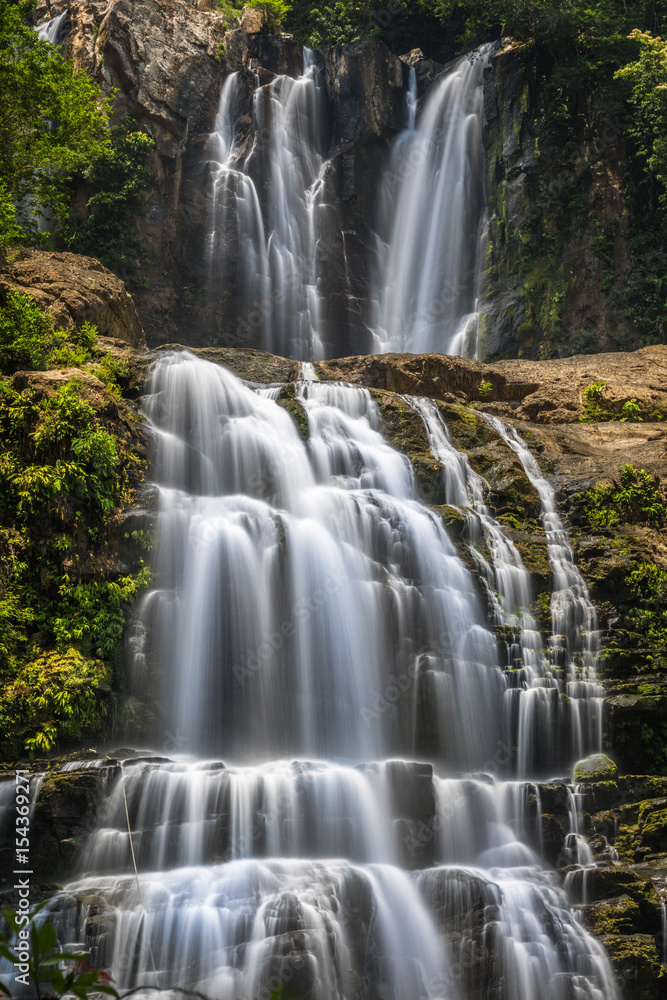 Fototapeta premium Double waterfalls in Costa Rica with grey rocks and green bushes and trees