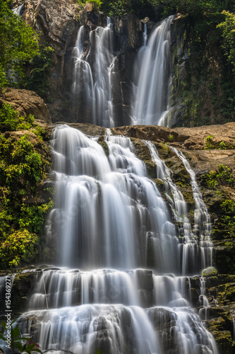 Double waterfalls in Costa Rica with grey rocks and green bushes and trees