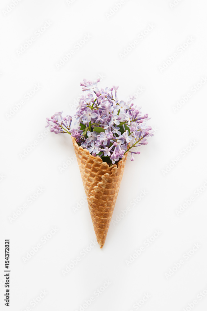 Card with Close up Bouquet of spring purple lilac flowers in the waffle cone on the white background. Top view. Flat lay. Space for text. Selective focus
