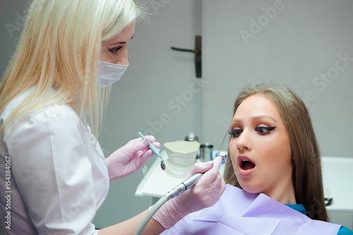 Frightened woman sitting in the dentist s chair while studying the doctor her teeth