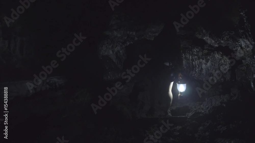 Girl walking through dark cave with lantern