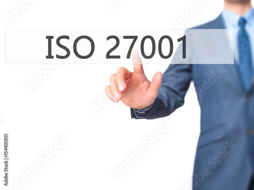 ISO 27001 - Businessman hand pressing button on touch screen interface.