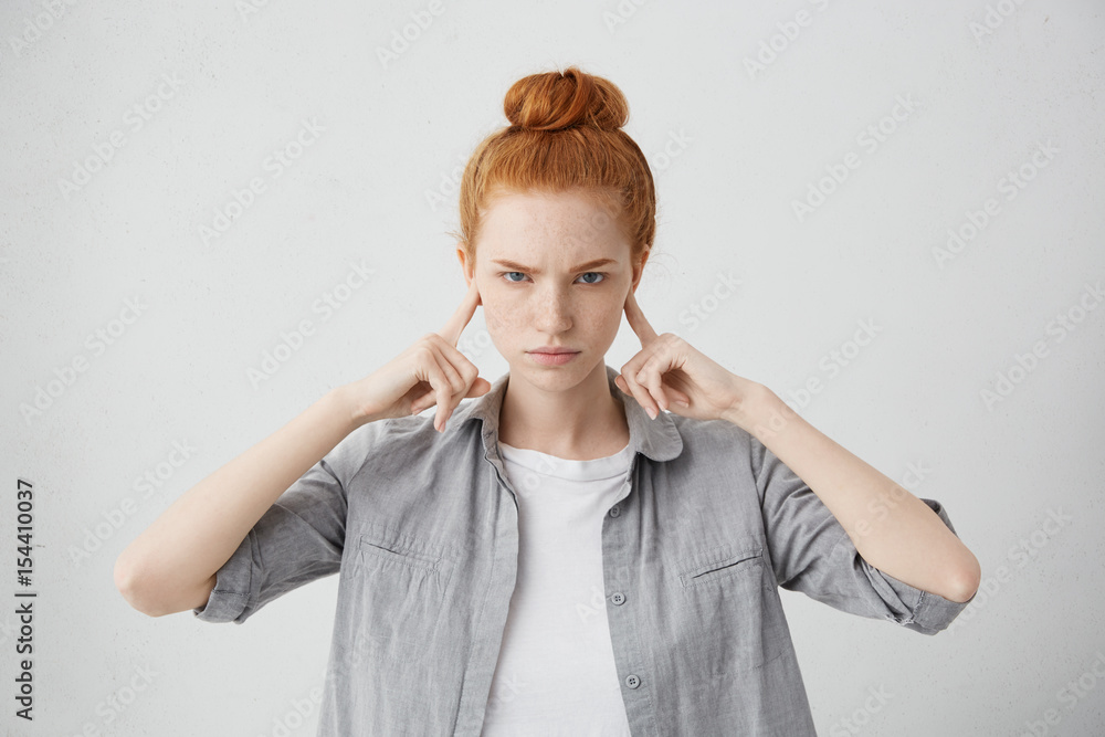 Studio portrait of angry and annoyed young female frowning and plugging her ears with fingers can't stand loud noise or ignoring stressful unpleasant situation or conflict. Negative human emotions Studio portrait of angry and annoyed young female frowning and plugging her ears with fingers can't stand loud noise or ignoring stressful unpleasant situation or conflict. Negative human emotions