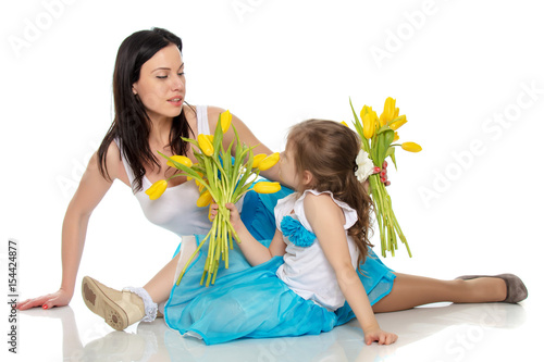 Mother and daughter smelling yellow tulips.