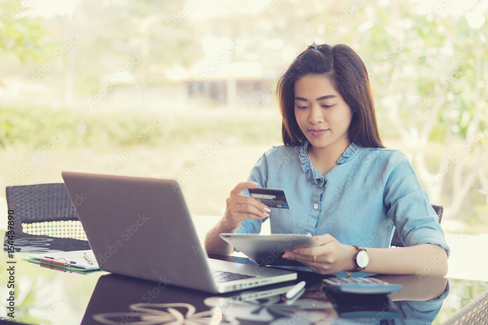 online shopping, woman smiling and looking in front of her as she uses her credit card with her laptop.shopping and retail concept,vintage color online shopping, woman smiling and looking in front of her as she uses her credit card with her laptop.shopping and retail concept,vintage color