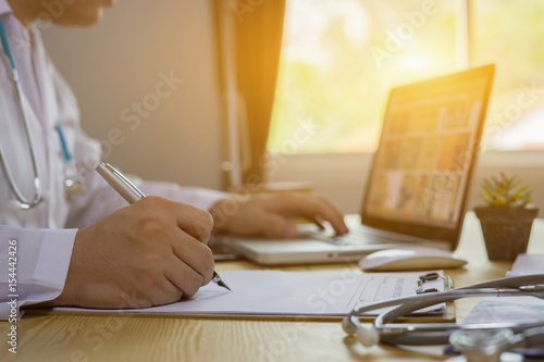 male medicine doctor hand holding silver pen writing something on clipboard closeup. Ward round, patient visit check, medical calculation and statistics concept. Physician ready to examine patient photo