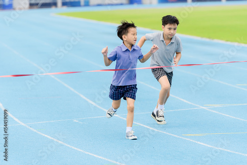 Young Asian boy running on blue track in the stadium