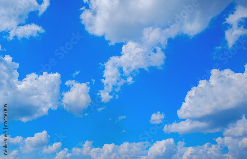 Clouds float over ground with bright blue sky background