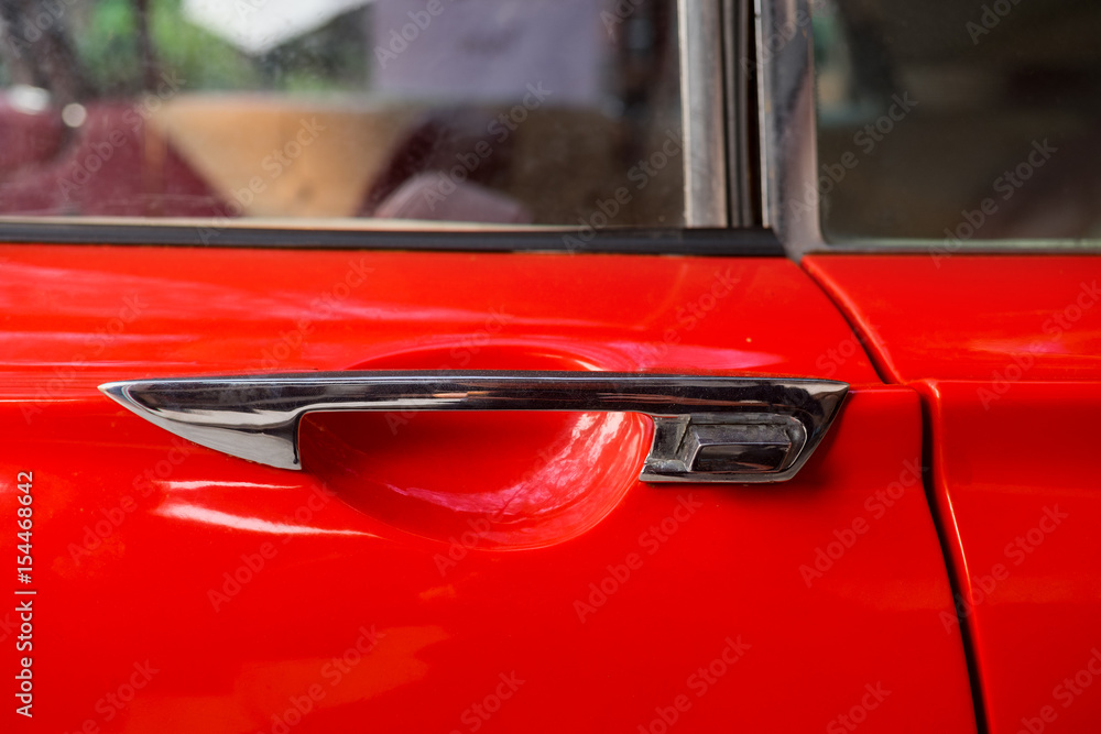 closedup classic retro car door latch engraved on the red frame.