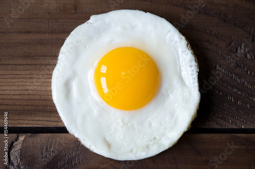 round shaped fried egg for healthy breakfast on dark wooden backgrond