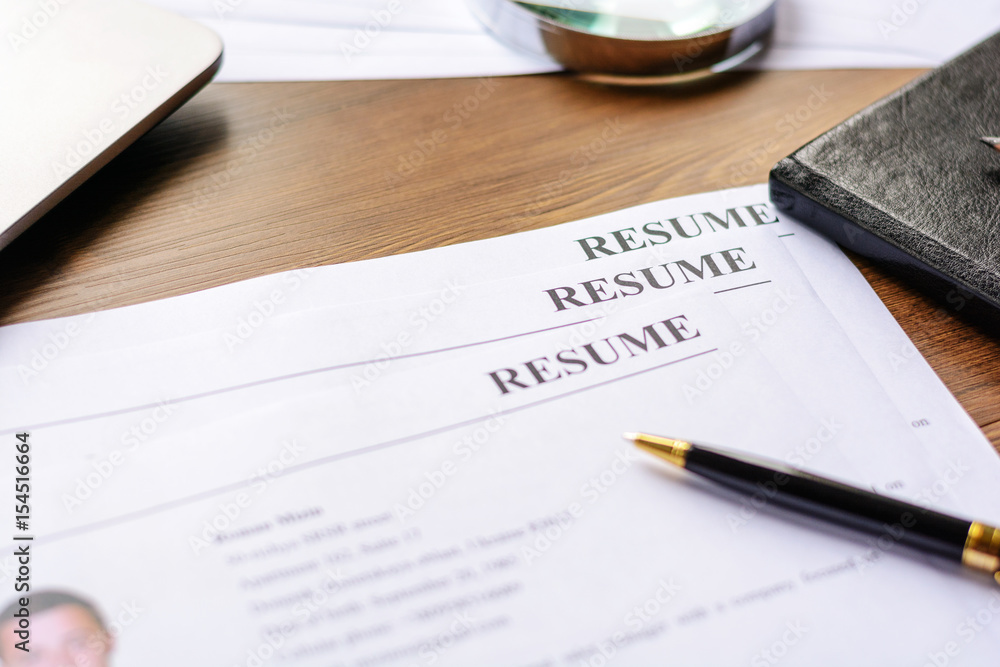 Resume, pen, magnifier, laptop on your desktop. job search Resume, pen, magnifier, laptop on your desktop. job search