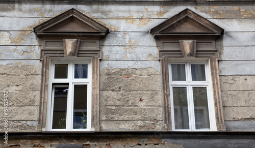 Two windows on the facade of the old ragged brick building