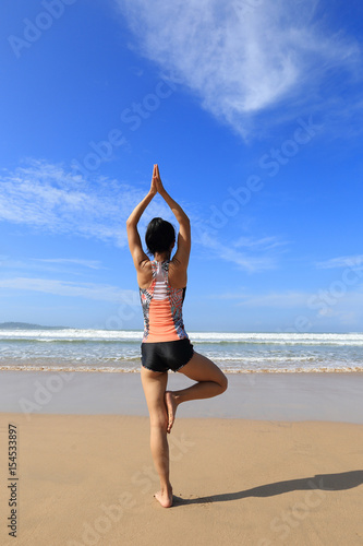 Young fitness woman wear swimsuit practice yoga on the beach