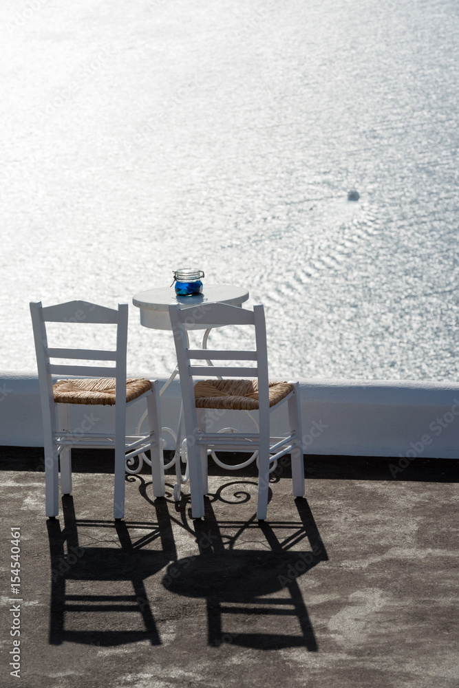 Terrace with two chairs, table and amazing view on Aegean sea, Santorini, Greece
