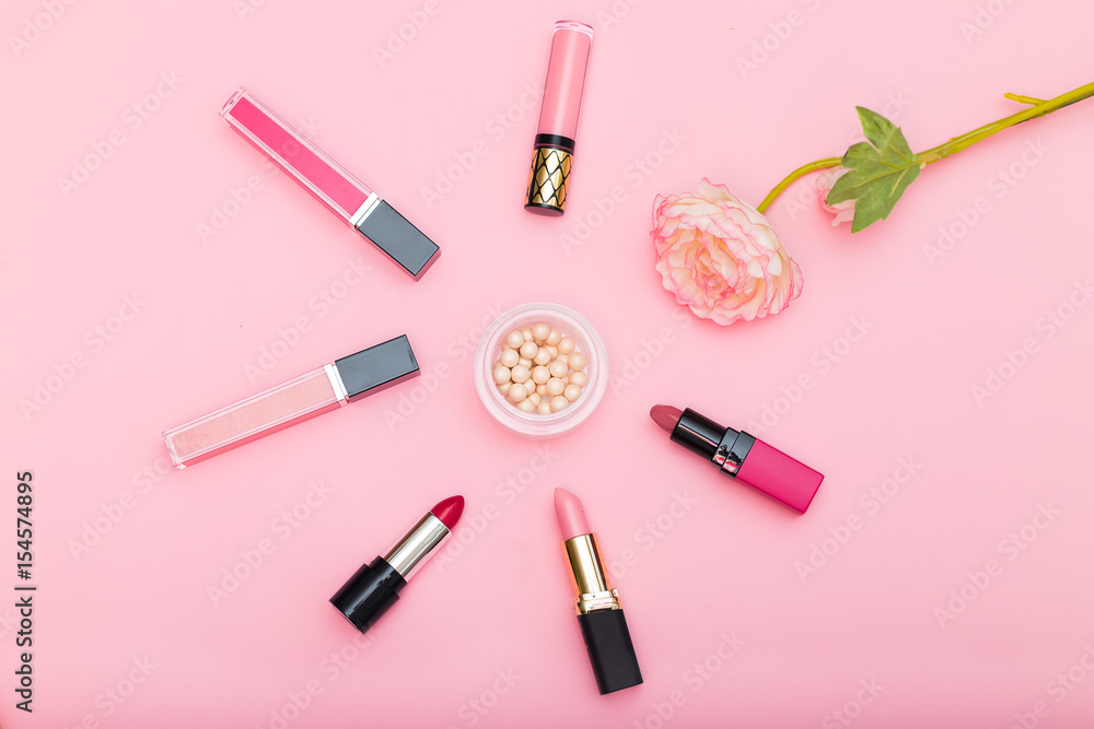 Lip gloss, lipstick and powder and a flower on a pink background Lip gloss, lipstick and powder and a flower on a pink background