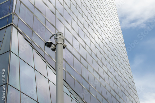 Security cameras post over modern glass office building background