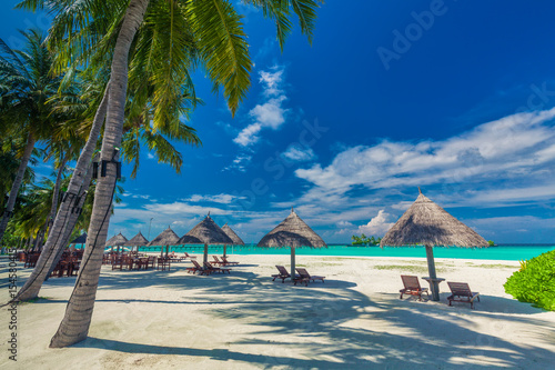 Fototapeta Naklejka Na Ścianę i Meble -  Chairs under umrellas and palm trees on a tropical beach, Maldives