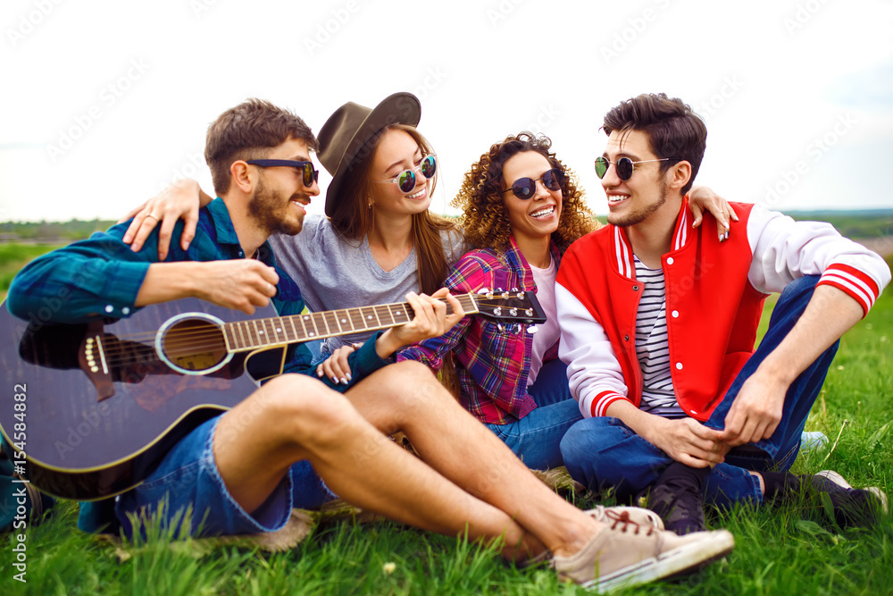 Obraz premium Group of friends enjoying party. The guy plays the guitar. Everyone has a great mood. Summer time.