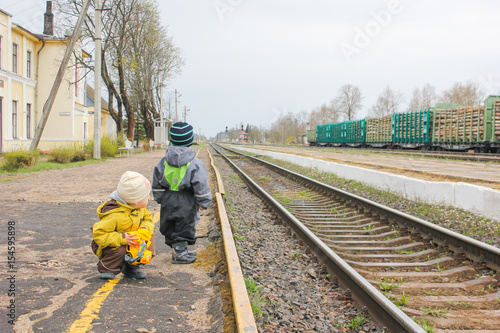 Two boys near the railroad at the station watching the train. Children at the train station waiting for the train. waiting for a Train..