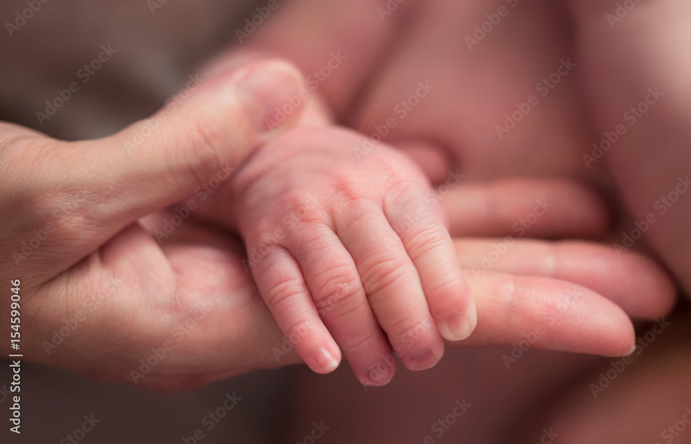 Little baby hand on mom's hand close-up