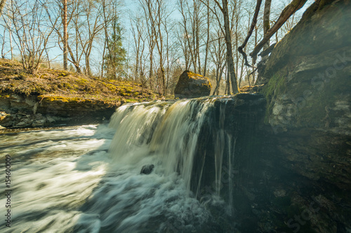 Waterfall in forest landscape long exposure flowing through trees and over rocks.