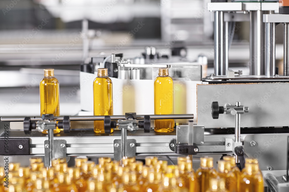 Factory process of production new cosmetics. Glass bottles standing on  conveyor line going to be twisted. Automated process on big factory.  Production of new shampoo on coveyor belt.Innovation concept Stock-Foto |  Adobe