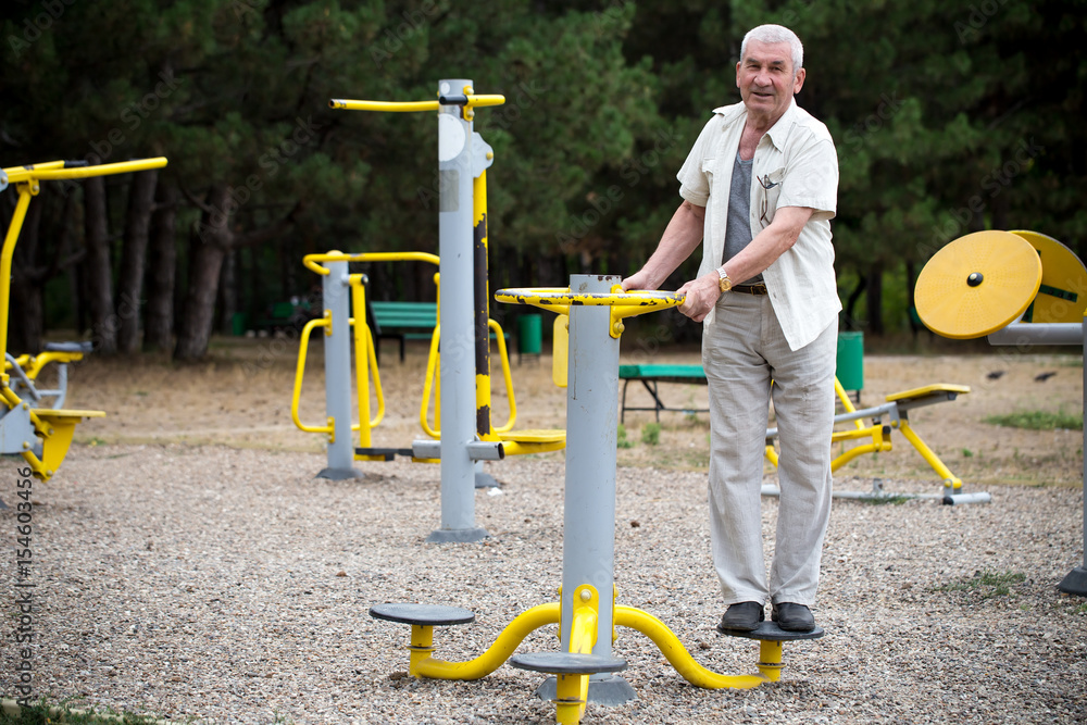 Fototapeta premium Old man making exercises on outdoor gym.
