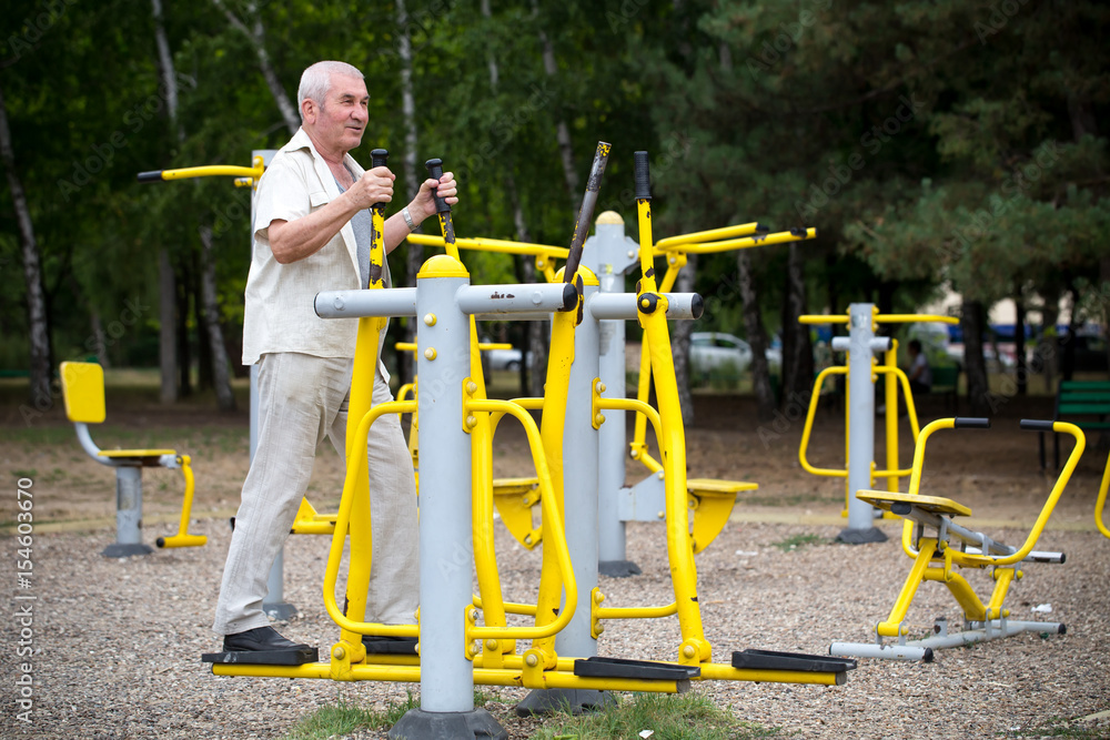 Fototapeta premium Old man making exercises on outdoor gym.