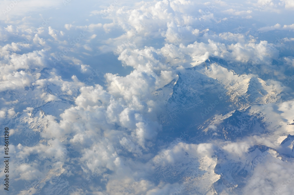 Sky scenery. Aerial view over the cumulus clouds and mountain peaks covered with snow on a sunny day. Swiss Alps. Sky scenery. Aerial view over the cumulus clouds and mountain peaks covered with snow on a sunny day. Swiss Alps.