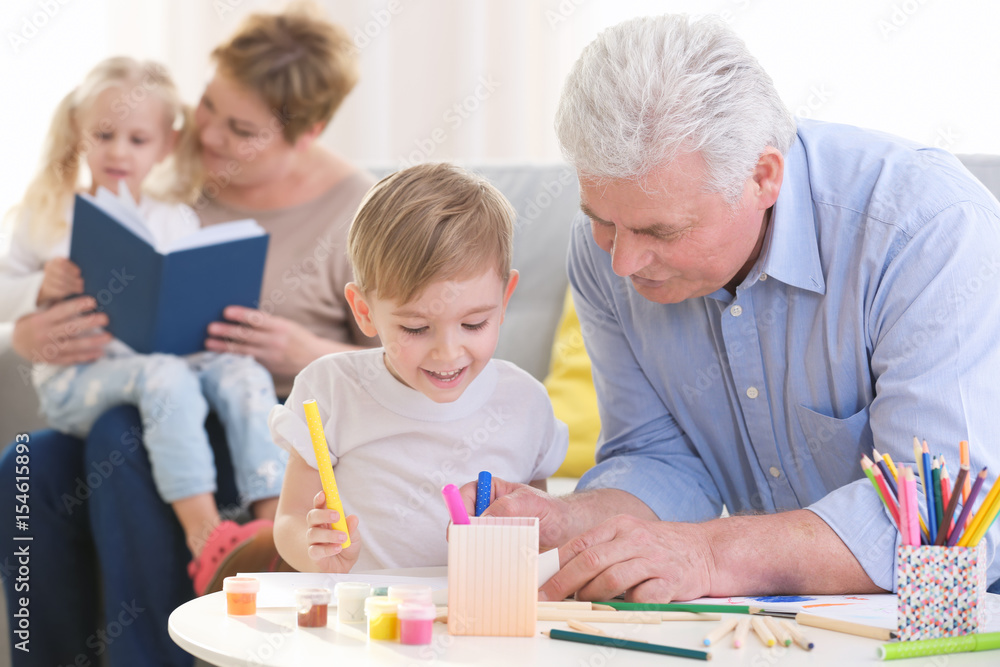 Happy senior man painting together with grandson at home Happy senior man painting together with grandson at home