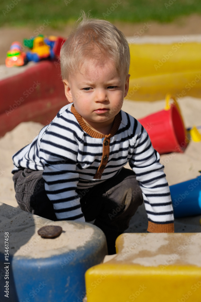 One year old baby boy toddler at playground sandbox