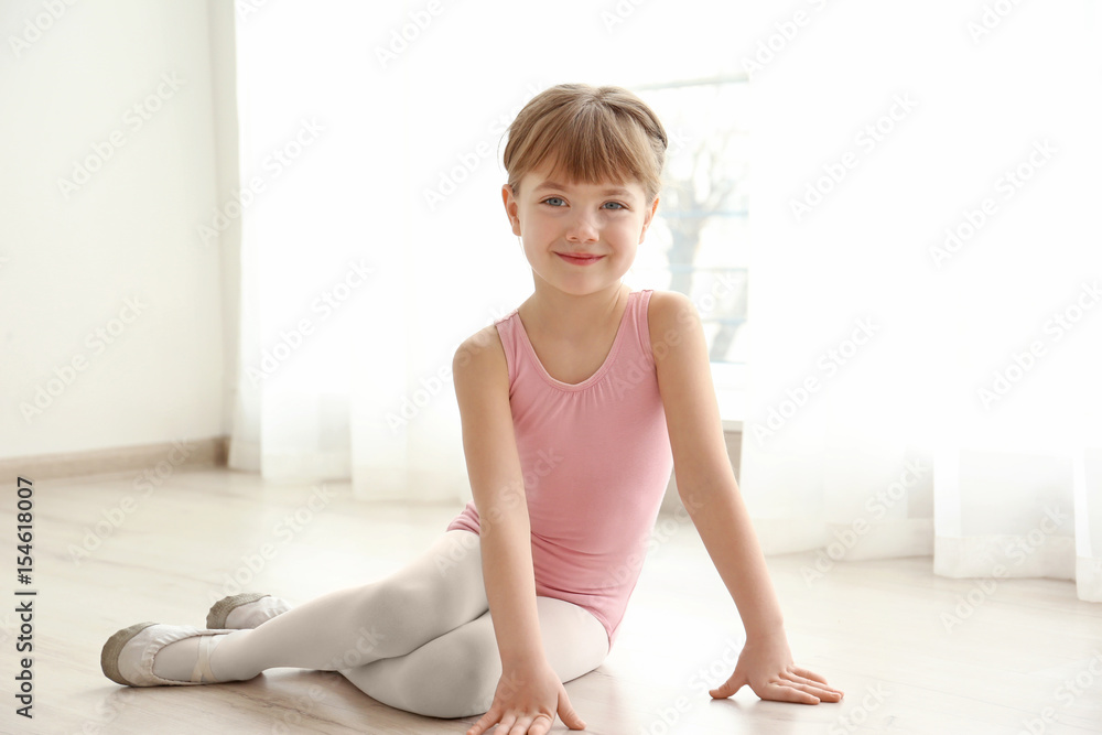 Fototapeta premium Cute little ballerina sitting on floor in dance studio