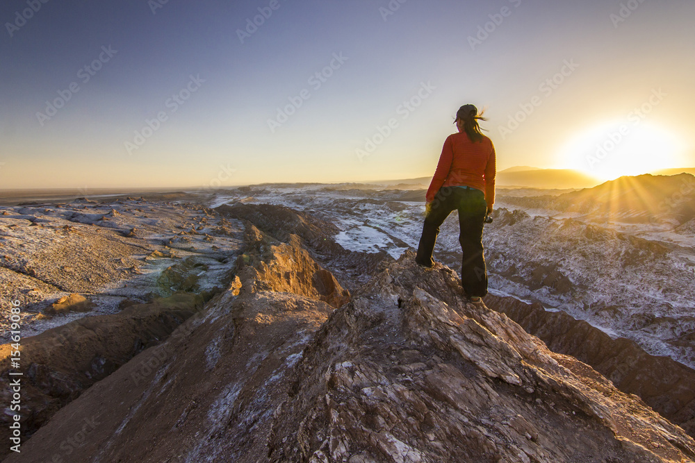 girl standing on a cliff in salty Moon valley in atacama desert at sunset