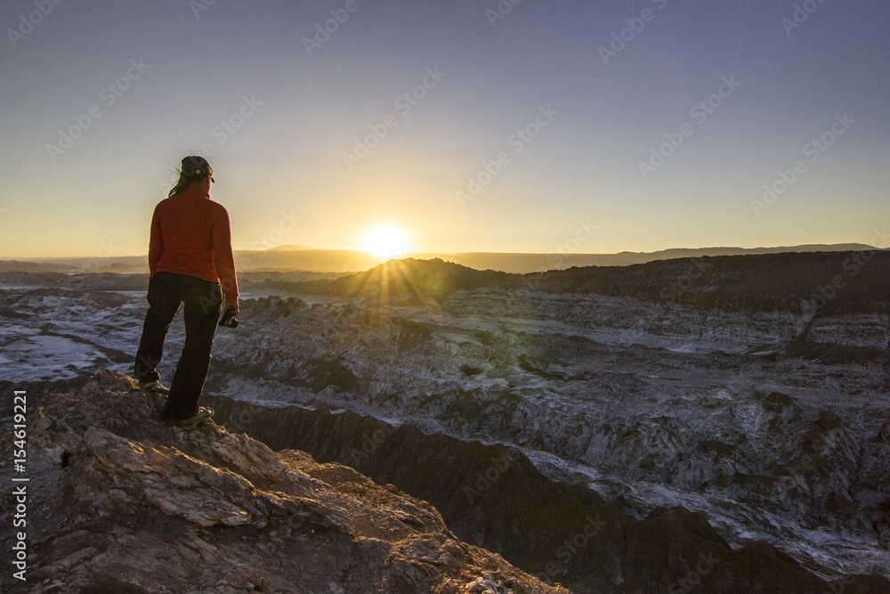 girl standing on a cliff in salty Moon valley in atacama desert at sunset