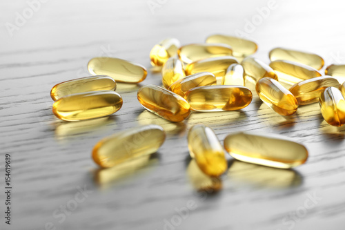 Fish oil capsules on white wooden table