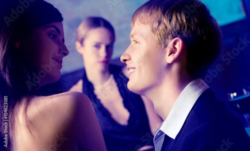 Young couple and woman looking at them at club