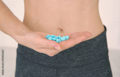 Diet concept. Woman holding pills in hand, close up