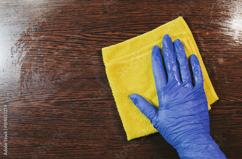 Closeup on woman's hands in blue protective rubber gloves cleaning kitchen cabinets. Instagram