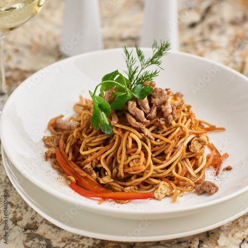Canvas Print Flat egg noodles with pork slices served on white plate with white garlic and re