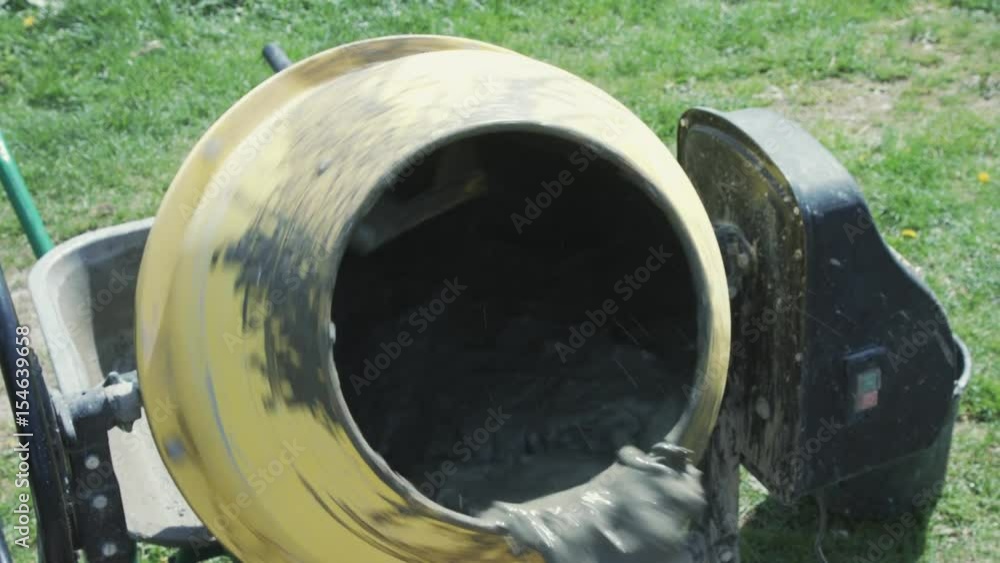 Industrial cement mixer machine at construction site. Concrete pouring.Construction worker mixing mortar. Pouring concrete mix from cement mixer. Industrial cement mixer machine at construction site. Concrete pouring.Construction worker mixing mortar. Pouring concrete mix from cement mixer.