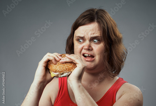 woman looks at the hamburger with disgust