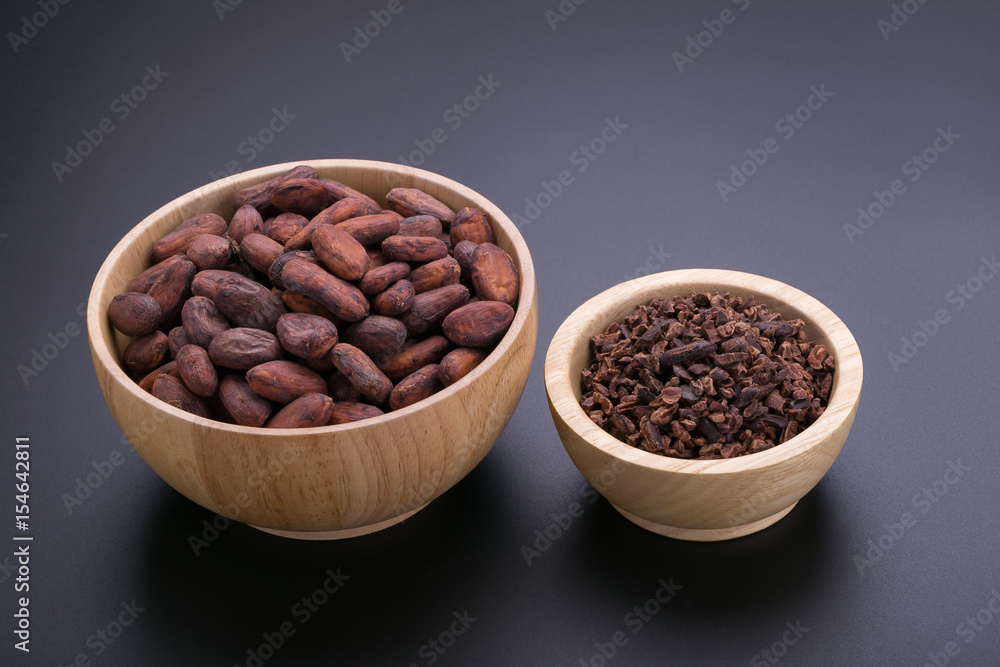 Chocolate bar and dried cocoa pod, cocoa nibs in wooden bowl on black background Chocolate bar and dried cocoa pod, cocoa nibs in wooden bowl on black background