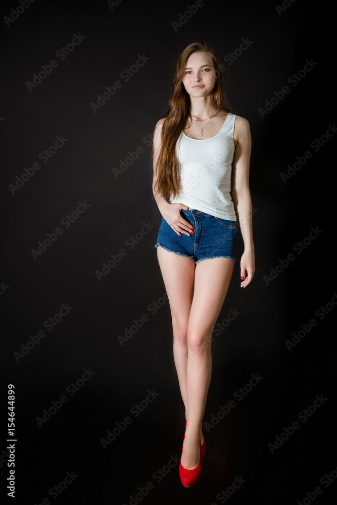 Attractive young woman smiling and posing in studio on black background Attractive young woman smiling and posing in studio on black background