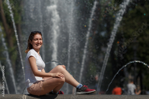 Beautiful woman sitting on the fountain background