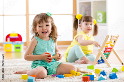 Children toddler and preschooler girls play logical toy learning shapes, arithmetic and colors in kindergarten or nursery